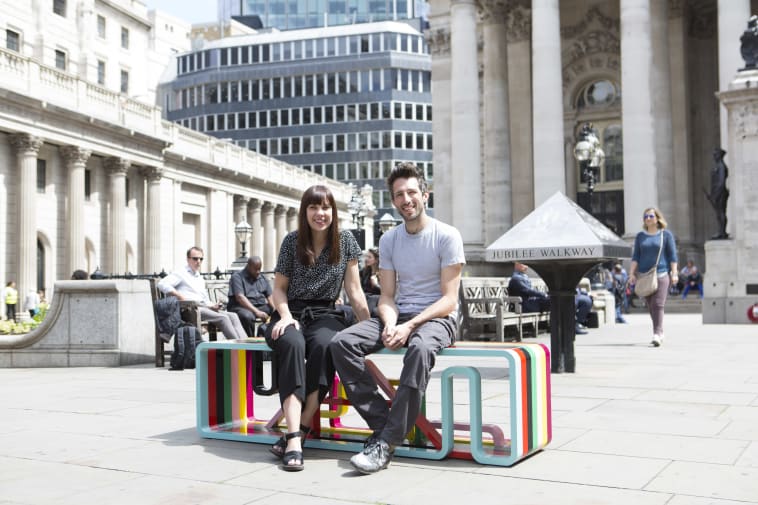 2 people sat on a multicoloured bench in London