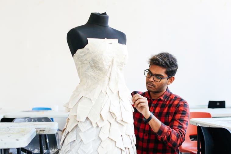 UAL student Pavithiran Charlas working on a dress displayed on a mannequin.