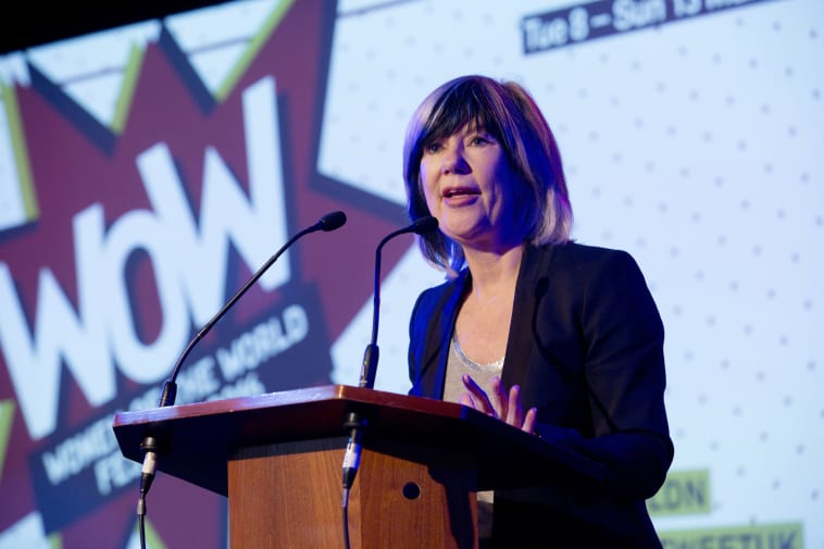 Woman at lectern with screen with WOW logo in background