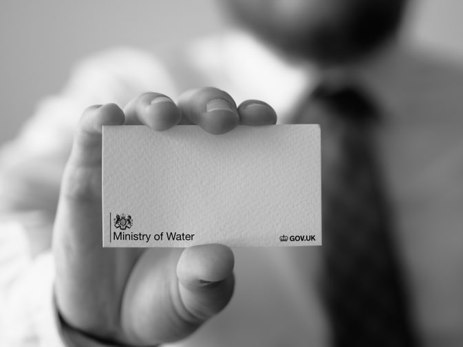 Black and white image of hand holding business card from Ministry of Water
