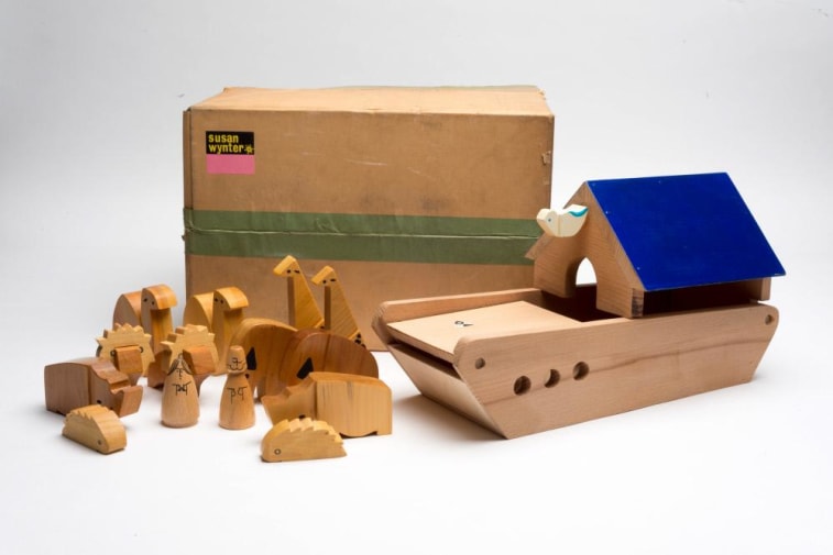 A toy wooden boat and animals, next to a brown cardboard box.