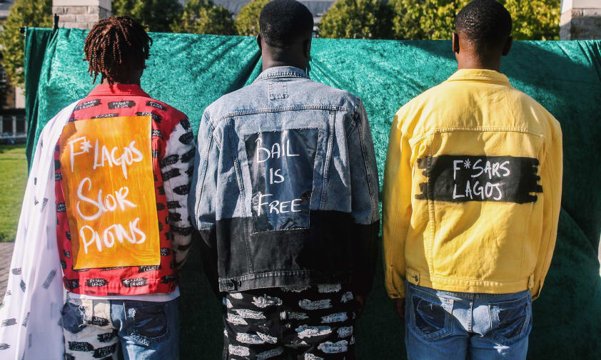 Three men with jackets with 'Bail is free' written on back