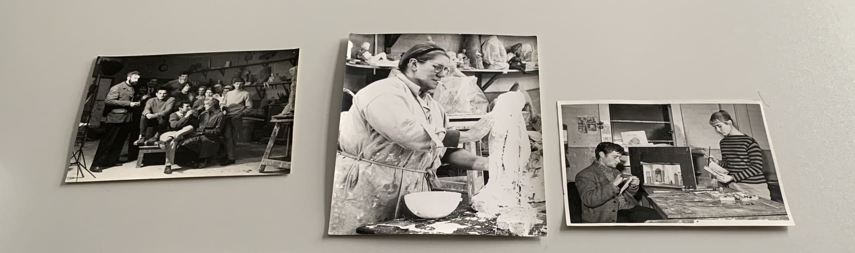 Colour photograph of a selection of black and white photographic prints showing tutors and students at work in sculpture studios, theatre productions and in group photo settings