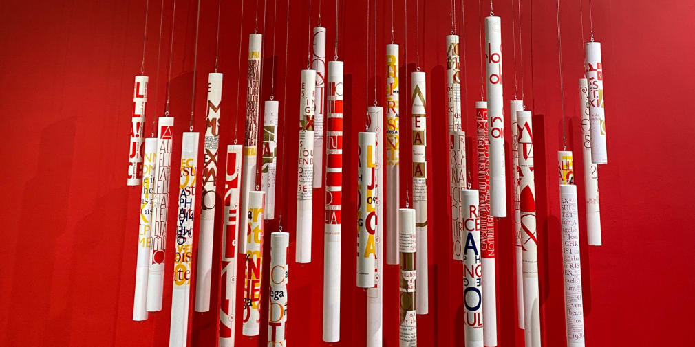 Hanging Paschal candles with lettering by Phil Baines on a red background