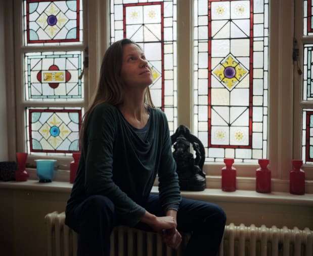 A woman sitting near a stain glass window 