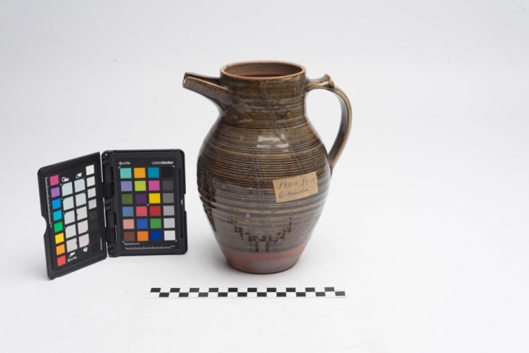 Side view of water jug, stoneware and brown/green glaze, with colour test card