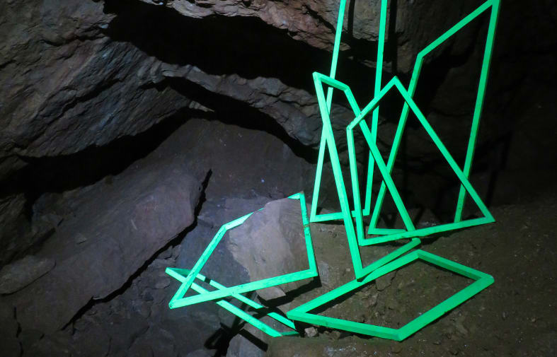 Green linear sculpture in a cave