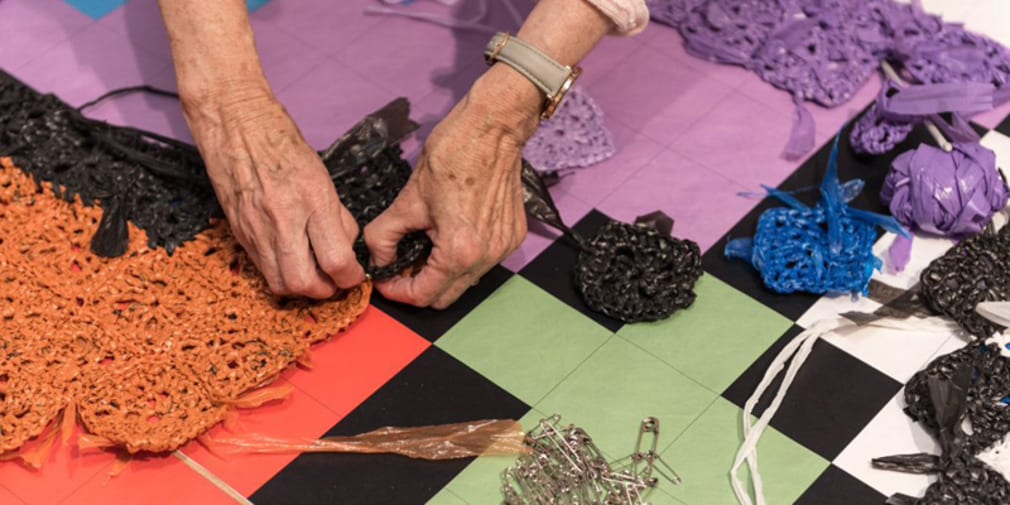 an elderly lady's hands crochetting plastic thread