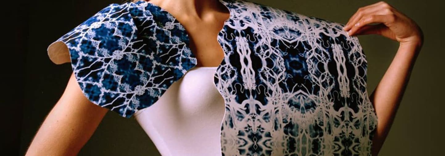 Female model wearing white top and white and blue printed cape