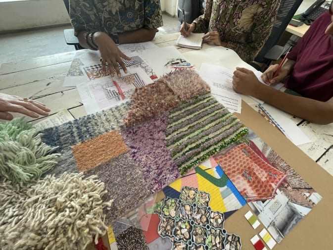 A selection of fabrics and swatches laid out on a table, with people's elbows visible