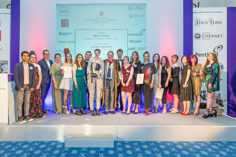 A mixed group of 20 people stand on stage at the Cordwainers National Footwear Student of the Year 2019