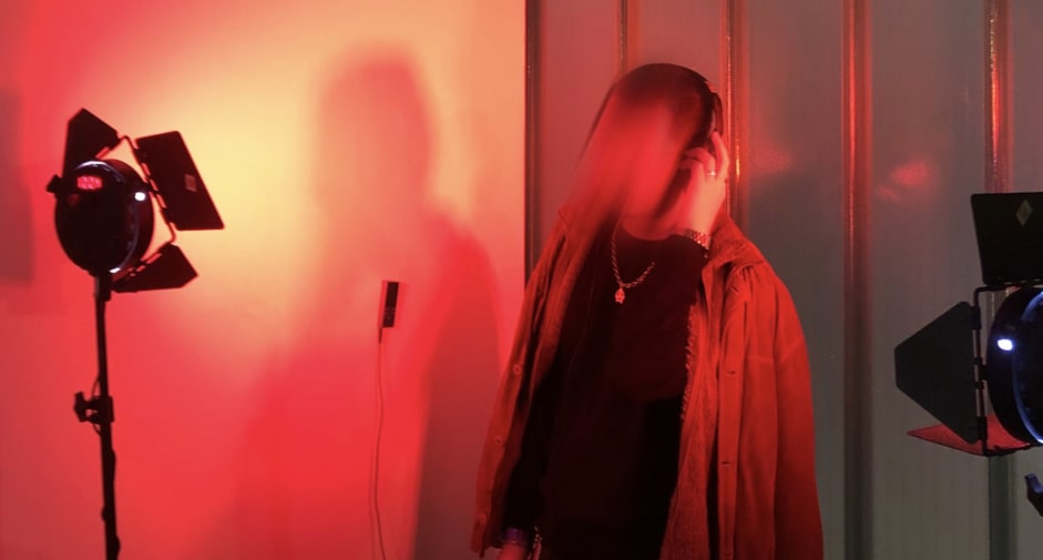 Person with headphones on in distorted photograph set in red lighting