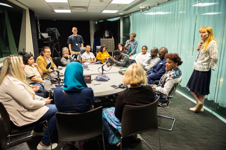 Participants of the Refugee Journalism Project sit in the Guardian Podcast studio with Guardian colleagues.