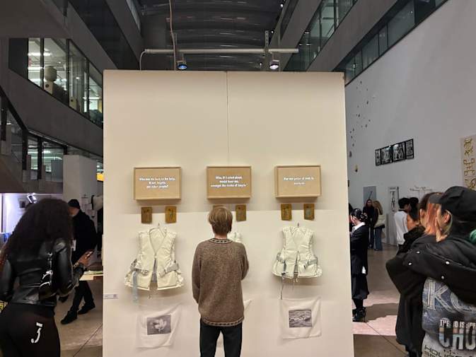 An image of an art installation on a wall surrounded by people viewing it