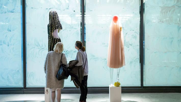 Two people looking at garments on mannequins