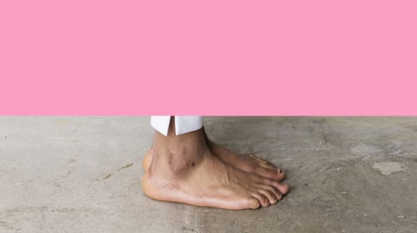 Photograph of a foot stood on concrete with a pink background