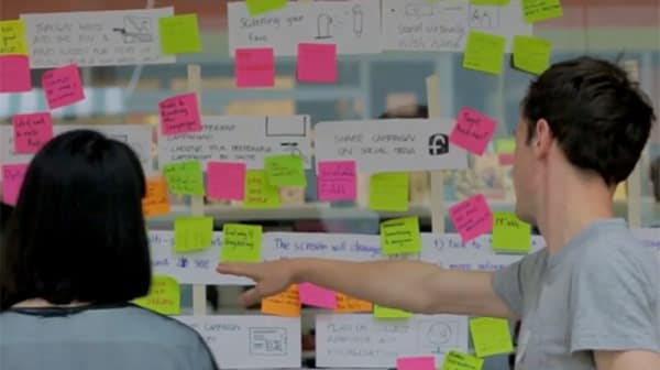 Students using colourful post-it notes to map out ideas for the design of a petition for Plan International UK.