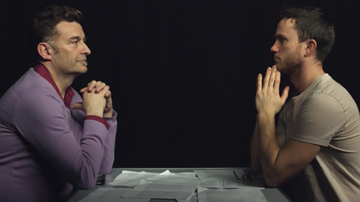 Two men looking at each other from across a table.