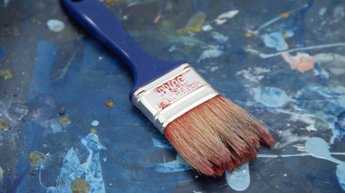 Paint brush laid on top of painting