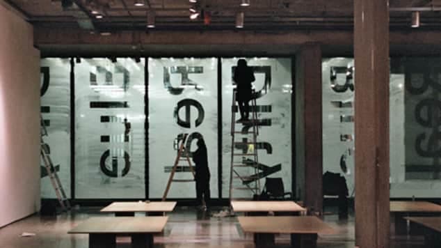people on ladders installing window decals