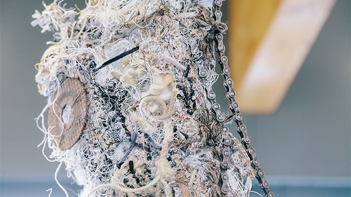 Different materials interwoven with unusual objects including a bike chain