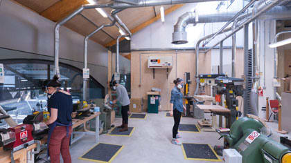 People using tools and machinery inside a large workshop at Central Saint Martins