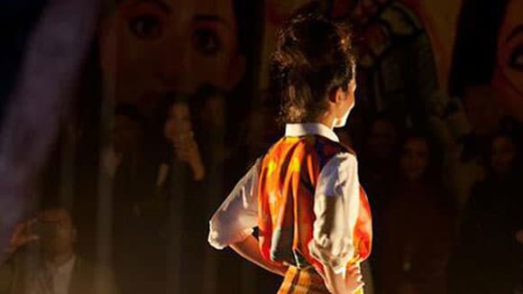 Photo of the back of a woman standing on stage