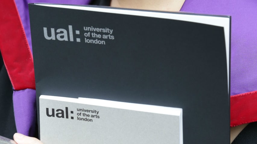 Graduate holding a certificate folder and awards programme.