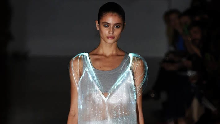 Photo of a model walking on a catwalk wearing a silver dress