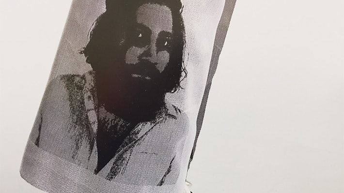 Black and white image of a man with a thick beard which has been printed onto a grey material