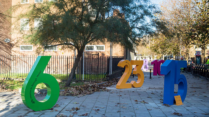 Several colourful and oversized numbers positioned near a hire bike stand.