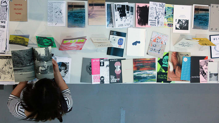 Aerial view of a woman standing over a table of papers and art work laid out