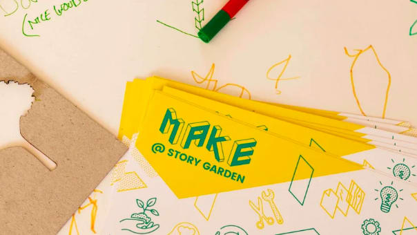 Photograph of papers on a desk showing a leaflet that reads 'make at story garden' on it