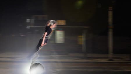 A woman zooming down a road on a futuristic vehicle
