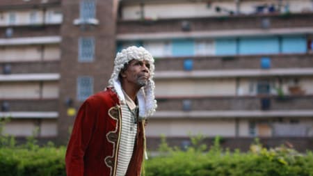 A man wearing a judges wig walking through an estate