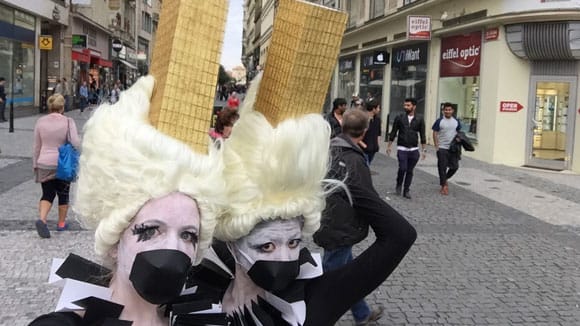 Photo of two women wearing ice cream cone costumes on their heads with black circles fixed over their mouths and black and white colours on
