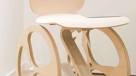 Partial image of a wooden wheelchair made from light coloured wood which makes it look more aesthetically pleasing than normal