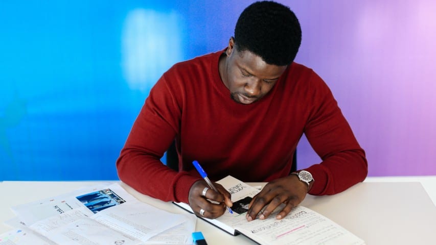 Student at desk writing in notebooks