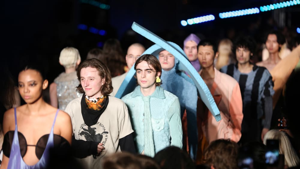 A line of male models walking the catwalk