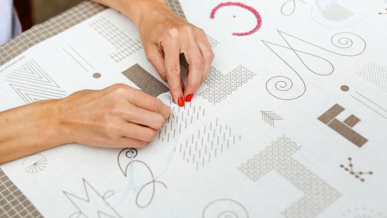 Woman embroidering text onto paper