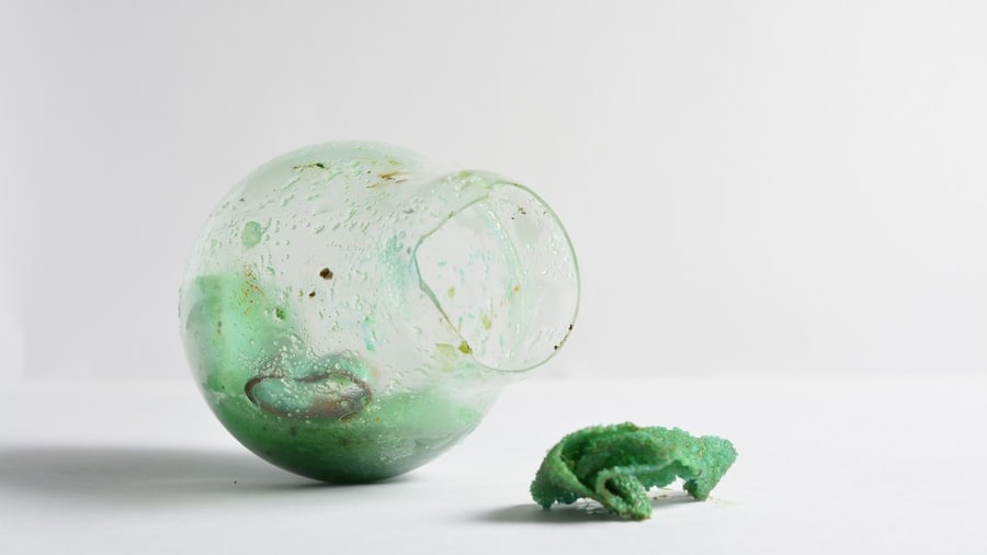 A smashed glass lightbulb with green oxidised crystals growing out of it