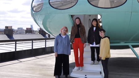 Three woman stood at the entrance of a Futuro House