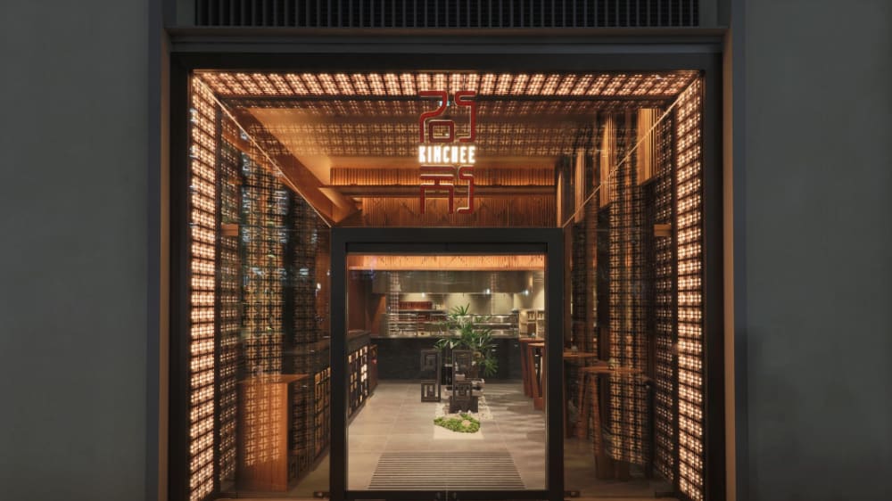 A large square entrance to a restaurant which is lit up by lots of lights around the door