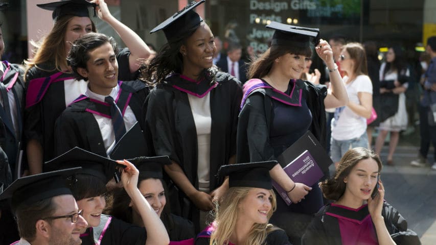 A group of graduates have their picture taken in their graduation robes.