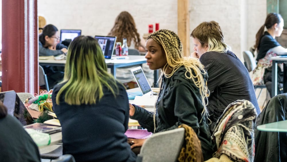 Students working at tables inside Central Saint Martins' Library
