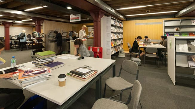 Students working at tables inside Central Saint Martins' Library