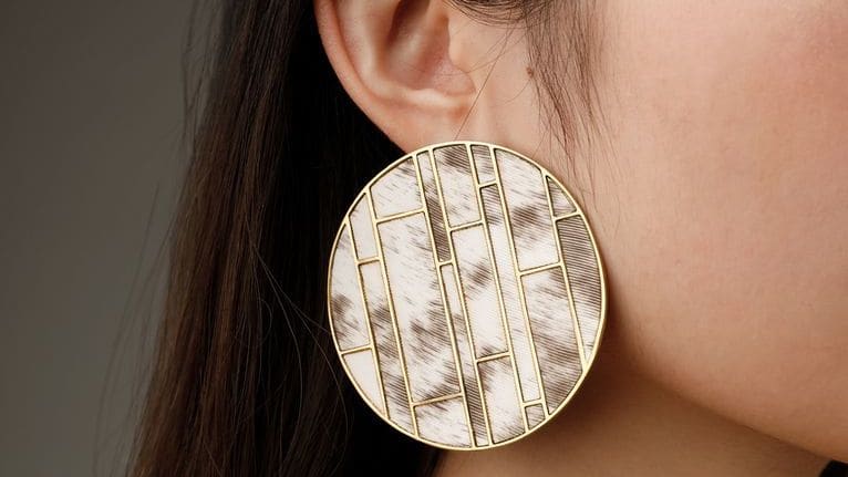 A young dark-haired woman whose face is not visible wears a large circular earring