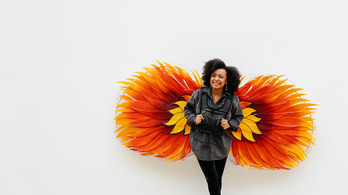 Woman standing in front of large orange and yellow flower graphic