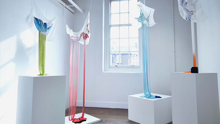 Photo of a white room with a large window with pieces of material hanging down