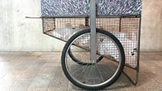 Photo of a metal cart on wheels with empty plastic bottles inside